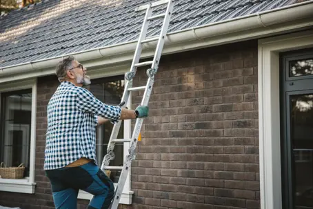 man on ladder inspecting roof